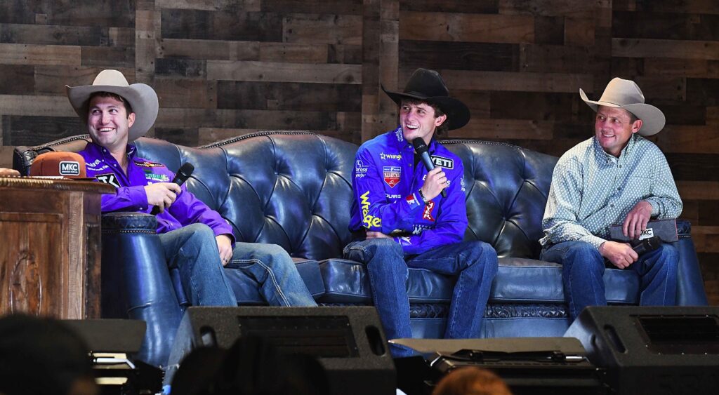 Cowboy-hat-wearing guests in a stage conversation at Cowboy Christmas